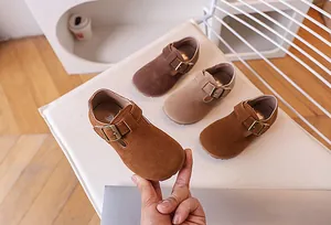 Détail de chaussures Mary Jane en daim pour enfants en tons marron, kaki et caramel