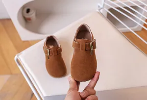 Détail de chaussures en daim marron pour enfants avec boucle en métal et cuir souple