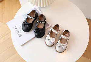 Detail of girls' Mary Jane shoes with large bow accents and elegant pearl buckles