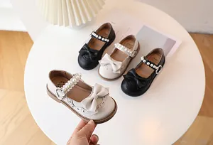 Detail of girls Mary Jane shoes with large bows, pearl straps and heart buckles