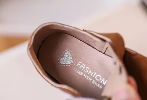 Détail de la semelle intérieure rose avec texte argenté sur chaussures en daim brun