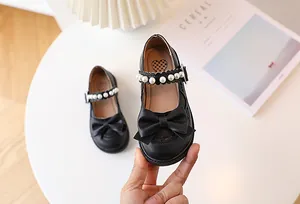 Detailed view of girls black Mary Jane shoes with large bow and pearl strap buckle