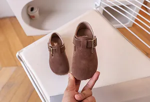 Vue détaillée de chaussures en daim marron pour enfants avec boucle et texture de cuir doux