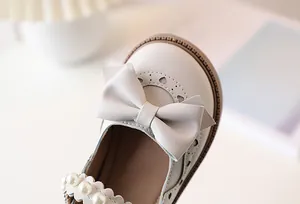 Close-up of girls Mary Jane shoes with heart cut-outs, bow detail, and pearl strap