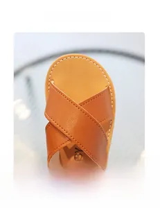 Detailed macro view of soft brown leather cross-strap toe on toddler Roman sandals