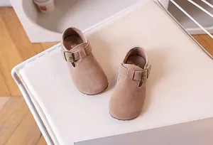 Détail de chaussures T-strap enfant en daim marron avec boucle en métal et motif de cœur