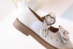 Detail of girls' Mary Jane shoes with heart-shaped cutouts, pearls, and bow decoration