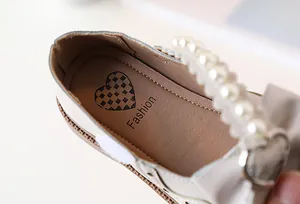 Close-up of girls princess shoes featuring a large bow with elegant white pearls