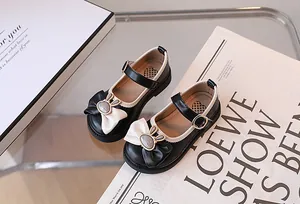 Dettaglio scarpe Mary Jane da bambina con fiocco nero e fibbia a coniglio in metallo