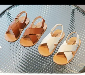 Detail view of children's leather sandals showing cross straps and white stitching accents