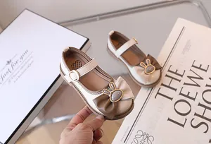 Dettaglio di scarpa Mary Jane bianca con fiocco marrone e grazioso coniglio dorato
