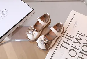 Dettaglio di scarpe Mary Jane beige con fiocco a contrasto e ciondolo a coniglio