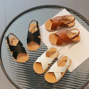 Childrens leather Roman sandals in black brown and white colors on a glass table