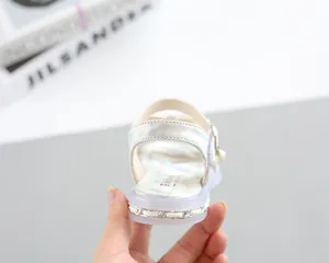 Detailed view of silver girl sandals featuring pearl charms and metallic chain sole trim