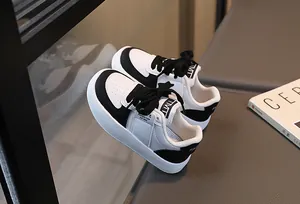 Détail de baskets en cuir noir et blanc pour enfants avec étiquette TMTT et sangle au talon