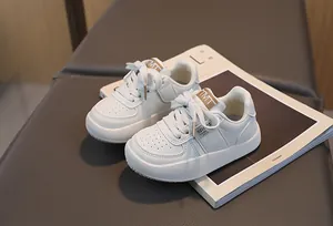 Détail de baskets en cuir blanc crème pour enfants avec étiquette TMT et imprimé sport