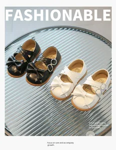 Detail of baby Mary Jane shoes with large bows and crisscross straps on glass background