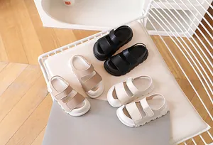 Detailed top view of kids closed-toe sandals in black, beige and khaki on a soft chair