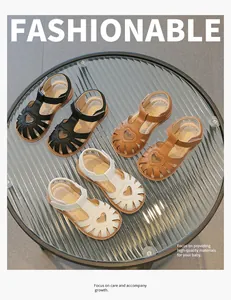 Nahaufnahme von Mädchensandalen mit Herzmuster in Schwarz, Braun und Weiß auf Glas