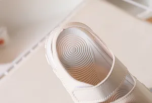 Close-up of beige children's sandals featuring non-slip spiral texture on the footbed