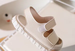 Close-up of beige children's sandals with lychee grain texture and velcro straps