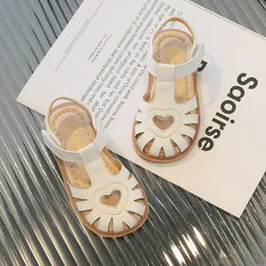 Beigefarbene Mädchen-Römersandalen mit Herz-Ausschnitten und Klettverschluss auf Magazin-Hintergrund