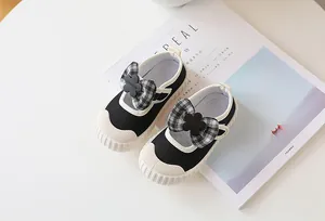 Detailed macro view of black canvas Mary Jane shoes with checkered bow and white rubber sole