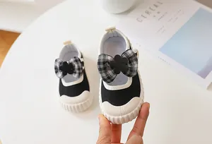 Detail of girls' Mary Jane canvas shoes with checkered bow and floral fashion buckle