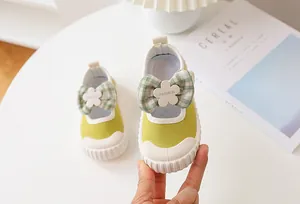Detail of lime green toddler canvas shoe with plaid bow and white floral accent