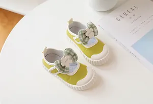 Detail of green canvas Mary Jane kids shoes with plaid bow and floral accents
