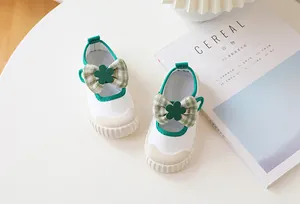 Detailed top view of kids canvas Mary Jane shoes with green bows and floral accents