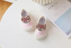 Close-up of pink canvas toddler shoes featuring plaid bow and floral fashion detail