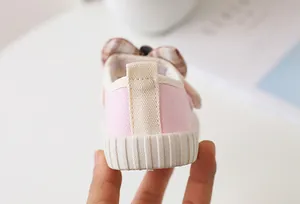 Detailed view of pink canvas shoes with checkered bow and anti-slip rubber sole for girls