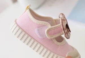 Close-up of pink canvas toddler shoes with checkered bow and non-slip rubber sole