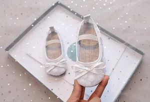 Detail van witte mesh baby Mary Jane schoenen met madeliefjesborduurwerk en een strik