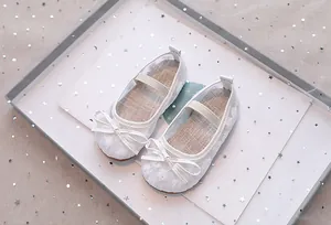 Detail van witte prinsessenschoenen voor meisjes met bloemenborduurwerk en een strik