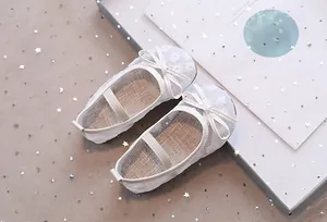 Detail van witte prinsessenschoenen voor meisjes met geborduurde bloemen en strik