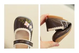 Detail of floral embroidery on brown girl's shoes and flexible soft rubber sole view