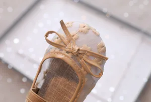 Detail van mesh sandalen voor meisjes met bloemenborduursels en kaki lederen strik