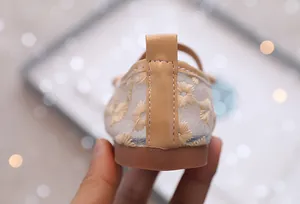 Detailweergave van kindersandalen met madeliefjesborduursel en leren hielstiksels