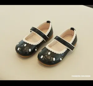 Close-up of girl's black Mary Jane shoes with floral embroidery and wavy white trim