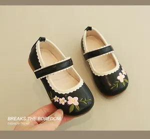 Detailed close-up of girls' black Mary Jane shoes with floral embroidery and wavy trim