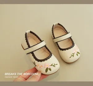 Detail of floral embroidery and scalloped trim on cream girl's Mary Jane shoes