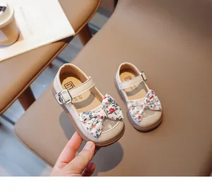 Detaillierte Nahaufnahme beige Mädchen Mary Janes mit Blumenschleife und Metallschnalle