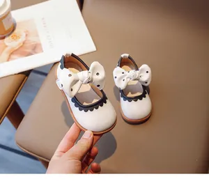 Detail von weißen Mädchen-Mary-Janes mit schwarz gepunkteter Schleife auf Leder
