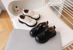 Detailed view of matte beige and black patent leather kids shoes with thick rubber soles