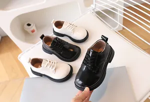 Detailed view of matte beige and black patent leather children's lace-up oxford shoes