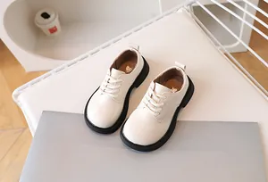 Close-up of children's creamy white dress shoes with lace-up style and durable black thick sole