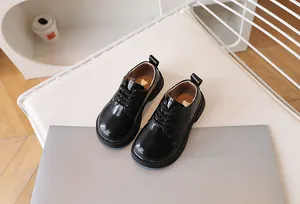 Close-up of black patent leather kids lace-up derby shoes on a white soft cushion