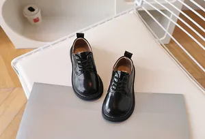 Top down view showing glossy black patent leather finish and lace-up details on kids shoes